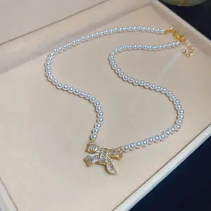 Elegant 18k gold plated zircon bow pendant detail on a classic white pearl necklace