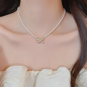 Close-up of 18k gold plated bow pendant pearl necklace featuring sparkling zircon stones