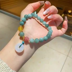 Detail view of light green chalcedony beaded bracelet with a white donut pendant on wrist.