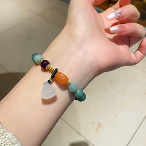 Detailed view of a colorful chalcedony beaded bracelet with a white gourd pendant on a wrist.