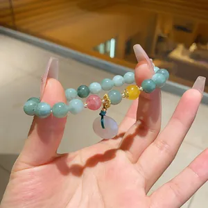 Detail of chalcedony beaded bracelet with a smooth donut pendant and lotus charms.