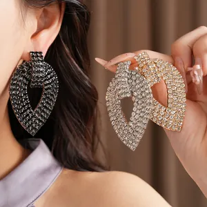Dettaglio di orecchini a foglia con strass oversize in nero, argento e oro lucido