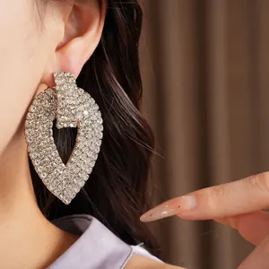 Dettaglio di un orecchino a goccia con strass scintillanti indossato da una modella di lusso