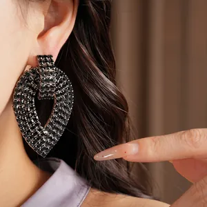 Dettaglio di grandi orecchini a goccia con strass neri indossati da una modella