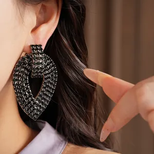 Primo piano di un elegante orecchino a goccia con strass neri indossato all'orecchio