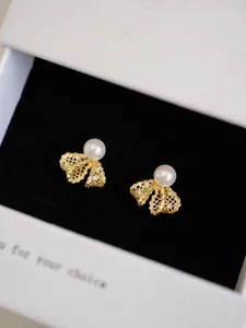 Detail of gold-plated bow earrings with white pearls and sparkling zircons in a box