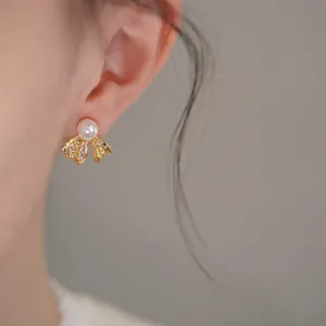 Detailed close-up view of delicate bow-shaped pearl stud earring with sparkling CZ accents