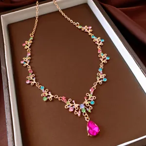 Collana vintage in oro rosa con strass colorati e un ciondolo a goccia rosa acceso.
