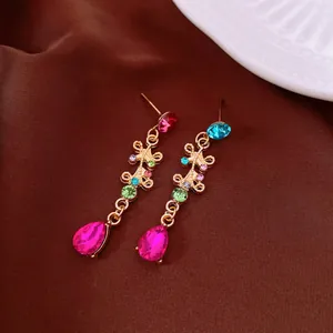 Dettaglio di orecchini pendenti vintage dorati con strass multicolore e gocce rosa