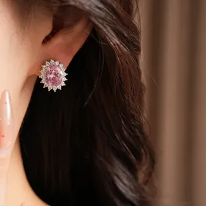 Elegant oval pink zircon stud earring featuring a shimmering halo design shown on ear