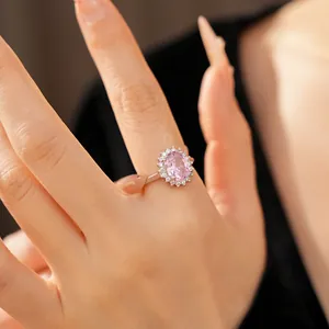Close-up of silver ring featuring pink oval zirconia surrounded by halo white stones.