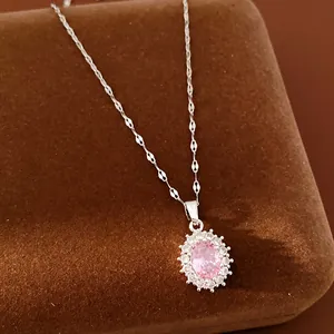 Close-up of elegant pink oval zircon pendant necklace on brown velvet display box.
