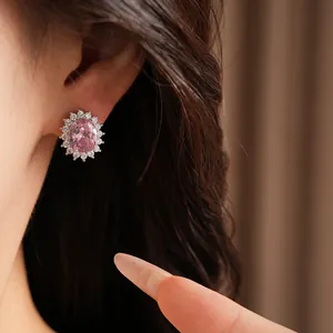 Close-up detail of an elegant pink oval zirconia stud earring worn on a model's ear.