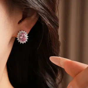Close-up of an elegant oval pink zircon stud earring worn on an ear for a detail view
