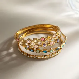 Close-up of multi-colored zircon stones set in 18K gold plated stainless steel bangles.