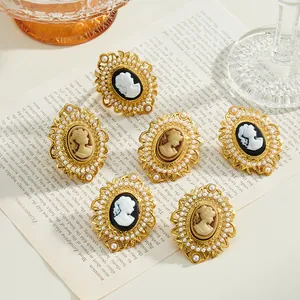 Close-up of vintage-style stainless steel cameo rings with pearl borders on book.