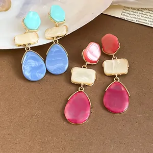 Primer plano de pendientes de resina de colores con un diseño de estilo dopamina.