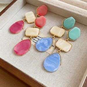 Primer plano de pendientes de resina de colores con textura de mármol en un joyero
