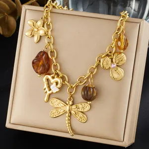 Close-up view of gold-plated dragonfly necklace featuring floral charms and heart pendant.