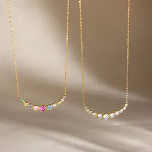 Close-up of elegant gold necklaces with curved multi-color and clear zircon pendants.