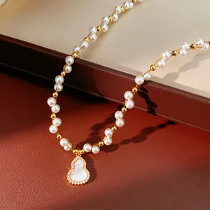 Macro detail of 18k gold plated pearl necklace with shell-inlaid gourd pendant