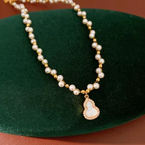 Detail view of a pearl necklace featuring a mother-of-pearl gourd pendant with zircons