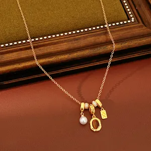 Détail d'un collier rétro doré avec une pierre brune ovale et un pendentif en perle.