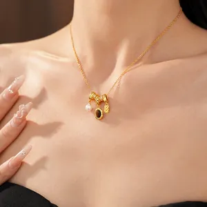 Vue détaillée d'un collier doré rétro avec perle et pendentif ovale en pierre brune