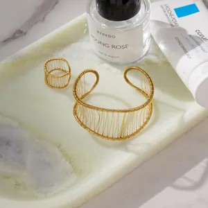 Close-up of gold wire-wrapped jewelry set including bracelet and ring on marble