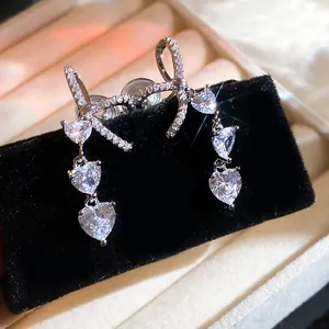 Macro view of silver bow earrings with sparkling heart-shaped zircon drops