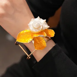 Brazalete abierto con flor de concha y pétalos naranjas vibrantes de estilo moda