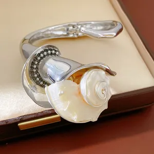 Primer plano de un brazalete plateado con flor de concha y detalles de diamantes brillantes