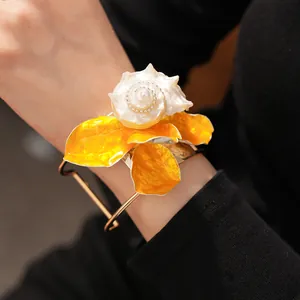Primer plano de un brazalete de flor de concha grande y elegante puesto en la muñeca