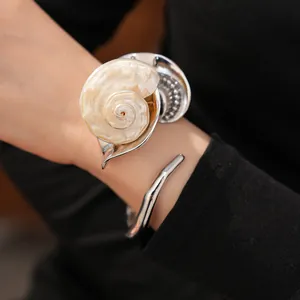 Detalle exquisito de un brazalete de concha natural grande con pavé de piedras