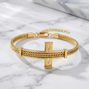 Nahaufnahme eines goldenen Edelstahlarmbands mit Kreuz-Ausschnitt und Drachenknochenkette