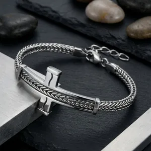Detail eines Herrenarmbands aus Edelstahl mit gebogenem Kreuzstab und Weizenkettendesign.