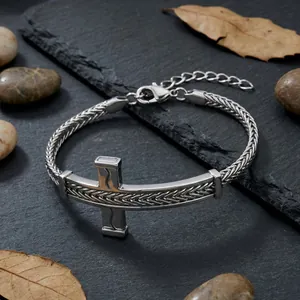 Nahaufnahme der gebogenen Kreuzplatte an einem Edelstahl-Drachenknochenkettenarmband Herren.