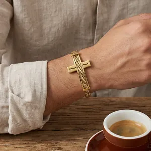 Detail eines goldenen Herrenarmbands aus Edelstahl mit hohlem Kreuz und Drachenknochenkette.