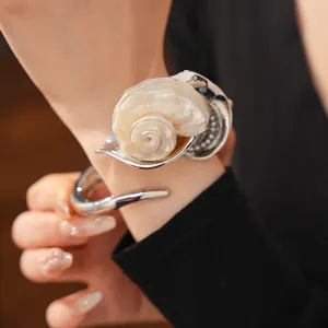 Vista detallada de un brazalete de flor de concha de gran tamaño usado en la muñeca