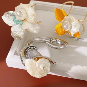 Primer plano de pulseras artísticas de conchas y flores con detalles de pedrería en bandeja