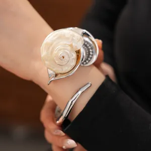 Vista detallada de un brazalete plateado con diseño de concha marina y cristales finos