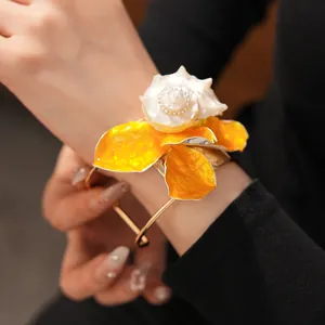 Primer plano de un brazalete de flor de concha con pétalos amarillos en muñeca