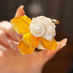 Vista detallada de un brazalete floral exagerado con centro de concha y pétalos amarillos