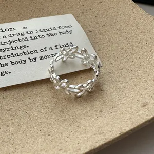 Close-up detail of a silver flower hollow open ring on a textured background