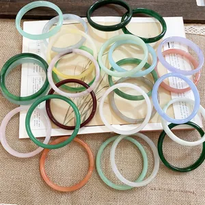 Eleganti bracciali rigidi in calcedonio tondi in vari colori su un libro d'epoca aperto