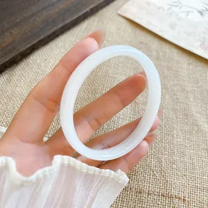 Dettaglio macro di un bracciale a cerchio in calcedonio bianco latte con finitura traslucida.