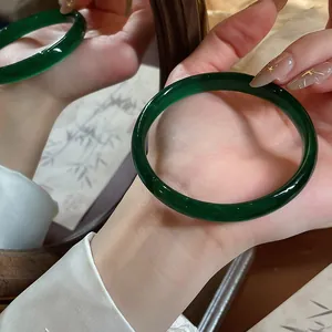 Primo piano di un bracciale circolare in calcedonia verde scuro riflesso in uno specchio