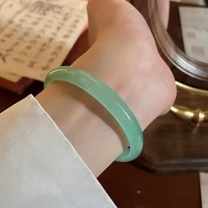 Elegante bracciale rigido in calcedonio verde traslucido mostrato su un polso raffinato