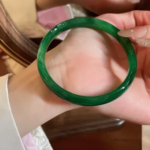 Dettaglio ravvicinato di un bracciale tondo in calcedonia verde scuro sul polso