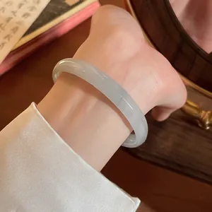 Elegante bracciale rigido in calcedonia grigia mostrato al polso su uno sfondo vintage
